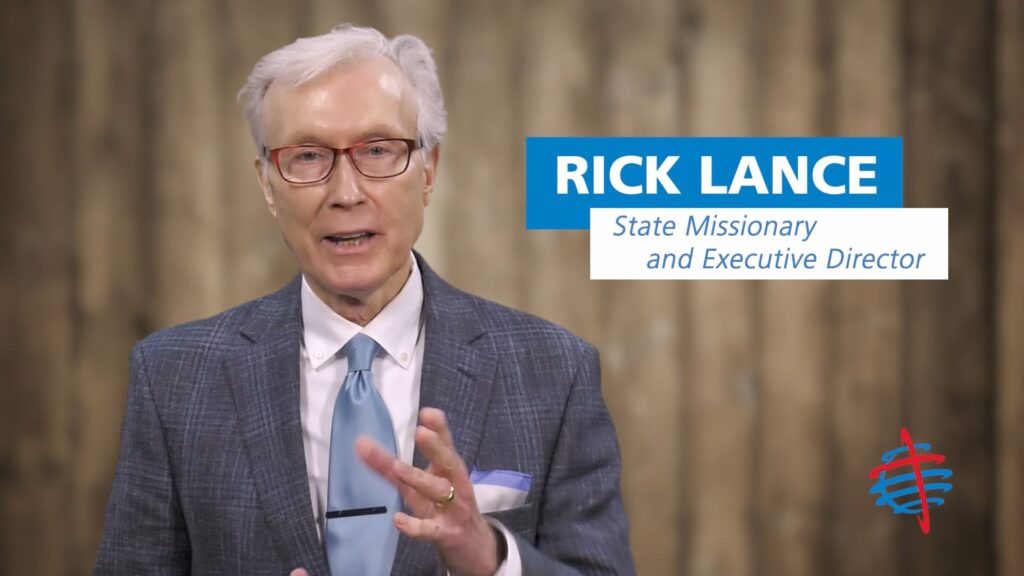Dr. Rick Lance standing in front of a woodgrain background